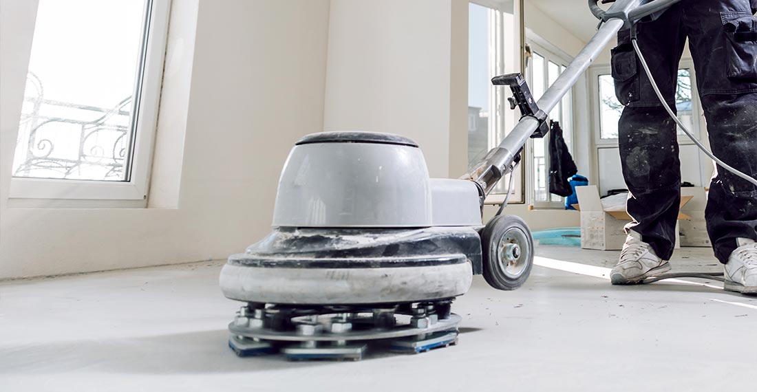 Worker using a concrete grinder during concrete floor preparation in Perth