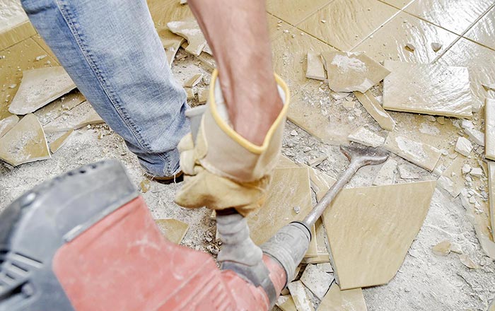 Worker smashing floor tiles to get ready for a new polished concrete floor