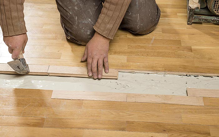 Worker preparing a concrete surface by removing timber flooring